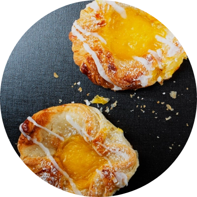 Two high-end French pastries with yellow custard centers are displayed on a dark surface.