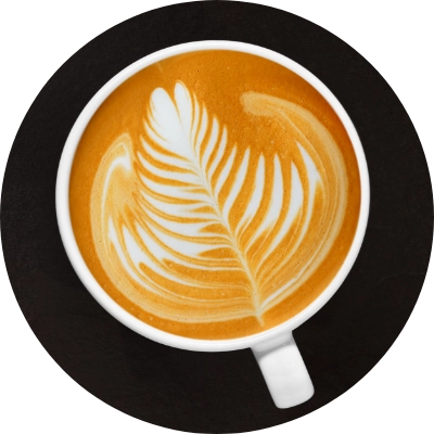 A cup of latte featuring intricate leaf-shaped latte art on its surface, viewed from above.