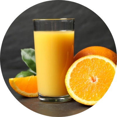 A glass of orange juice is placed next to whole and sliced oranges with leaves on a dark background.